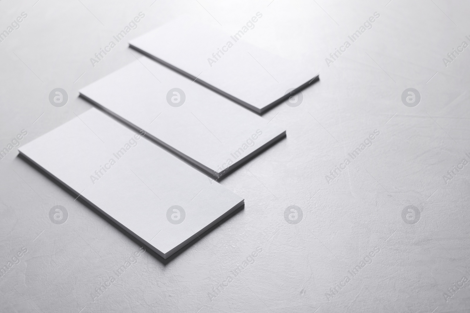 Photo of Blank business cards on light grey textured table, closeup. Mockup for design