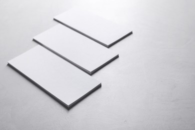 Blank business cards on light grey textured table, closeup. Mockup for design