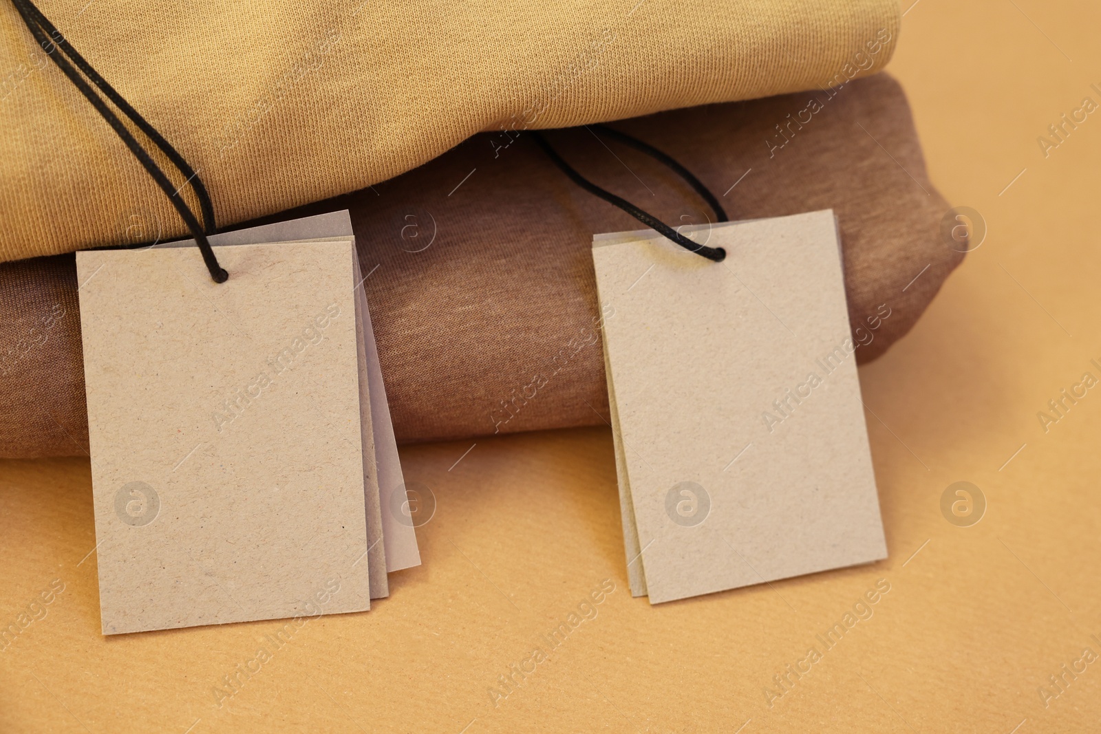 Photo of Garment with cardboard tags on kraft paper sheet, closeup. Space for text