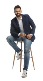 Handsome young man sitting on stool against white background