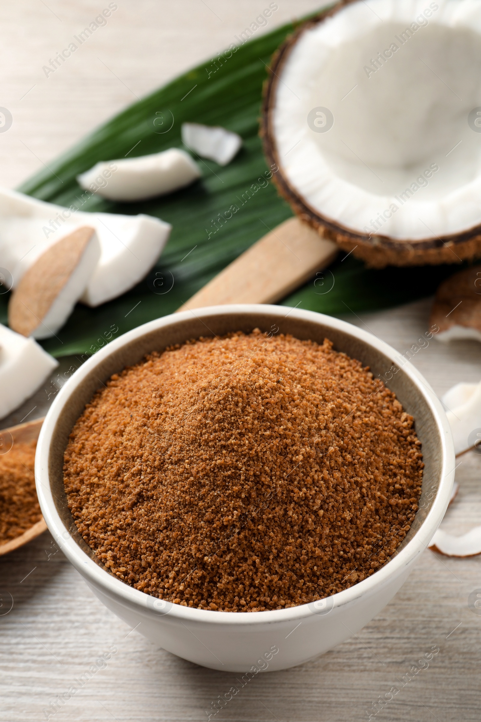 Photo of Natural coconut sugar in bowl on white wooden table