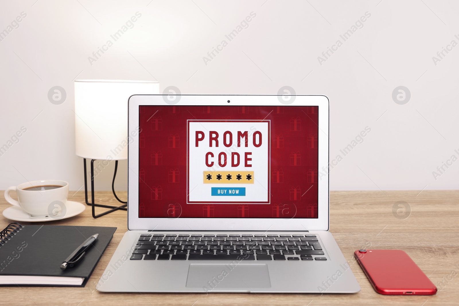 Photo of Laptop with activated promo code on wooden table indoors