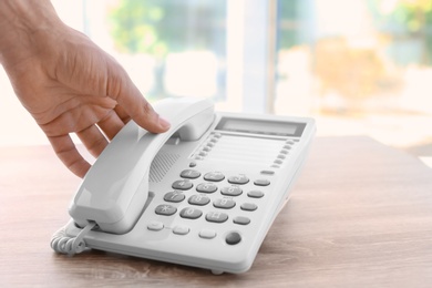 Man picking up telephone at table indoors