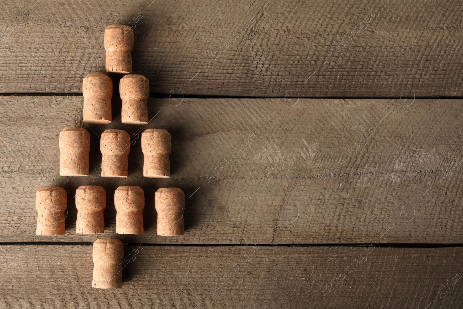 Photo of Christmas tree made of sparkling wine corks on wooden table, top view. Space for text