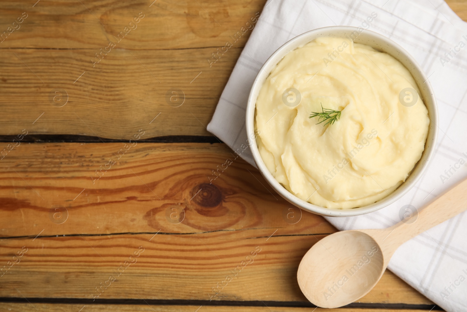 Photo of Freshly cooked homemade mashed potatoes, spoon and napkin on wooden table, flat lay. Space for text