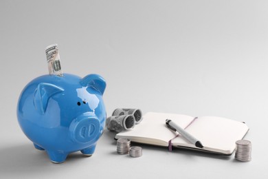 Photo of Financial savings. Piggy bank, dollar banknotes, coins and stationery on grey background