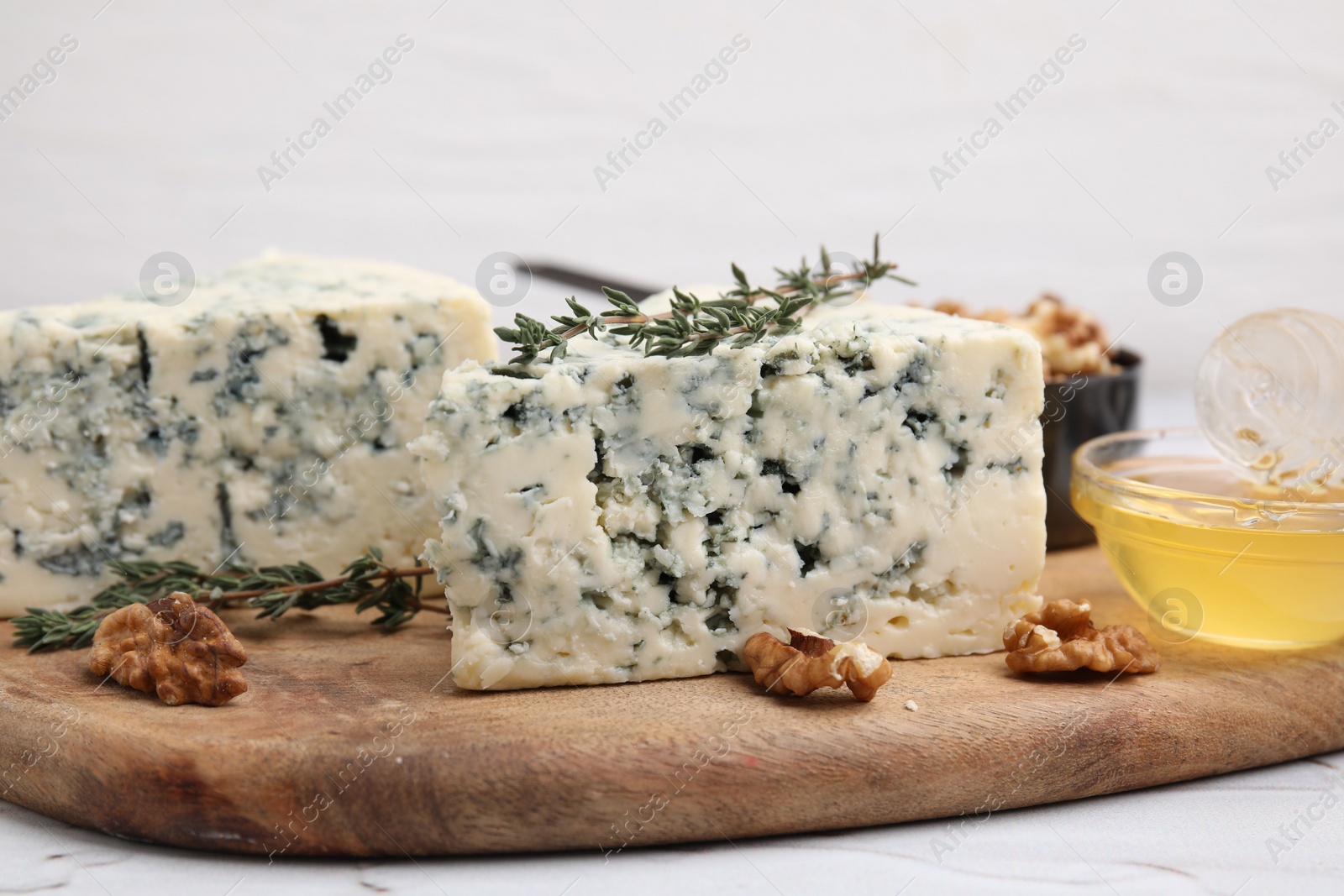 Photo of Tasty blue cheese with thyme, honey and walnuts on white table, closeup