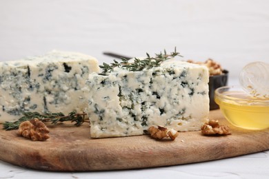 Photo of Tasty blue cheese with thyme, honey and walnuts on white table, closeup