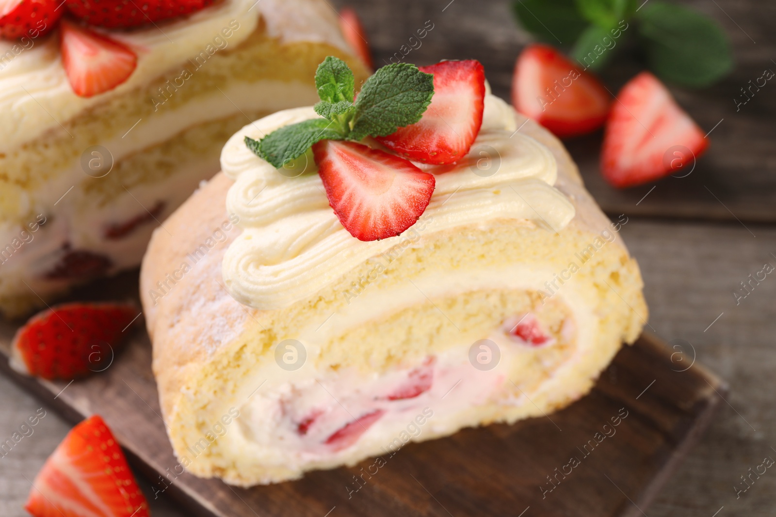 Photo of Delicious cake roll with strawberries and cream on table, closeup