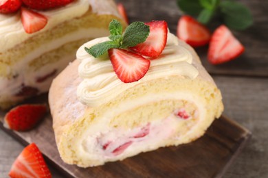 Delicious cake roll with strawberries and cream on table, closeup