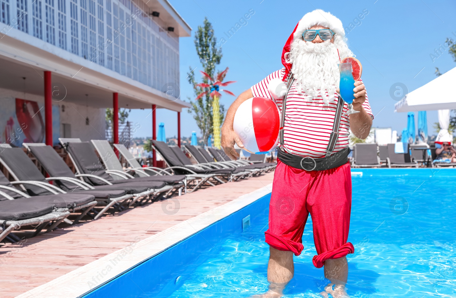 Photo of Authentic Santa Claus with cocktail and beach ball in pool at resort