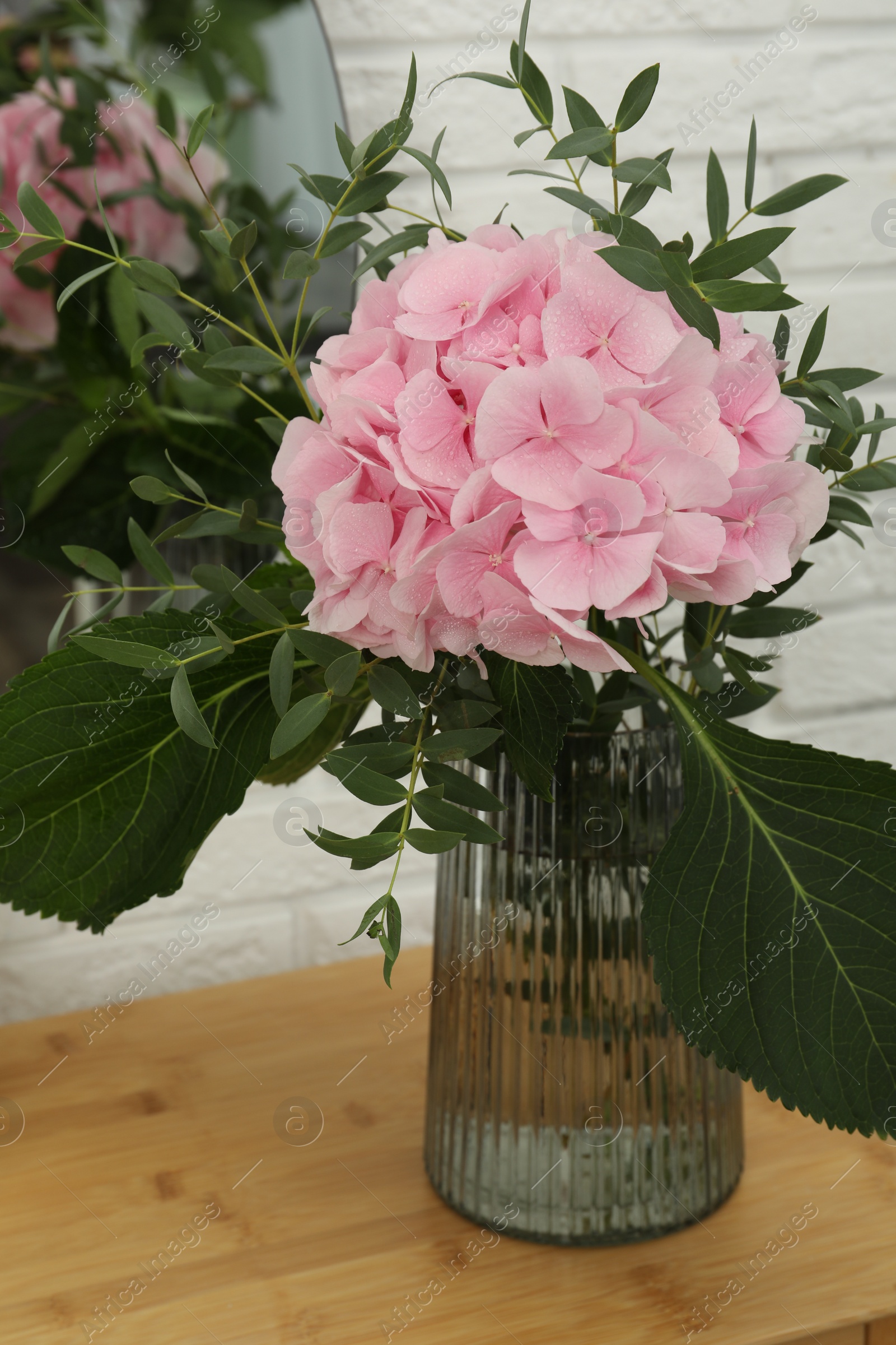 Photo of Beautiful pink hortensia flowers in vase on dressing table indoors