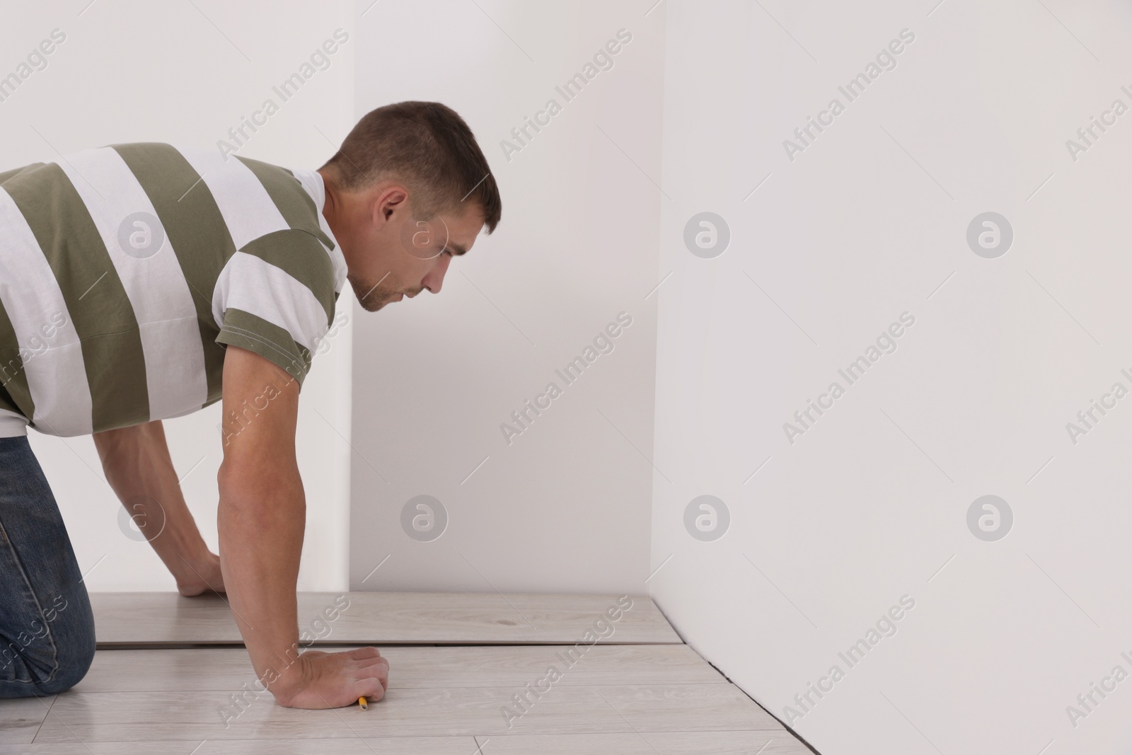 Photo of Professional worker installing new laminate flooring indoors