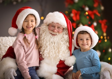 Photo of Little children sitting on authentic Santa Claus' knees indoors