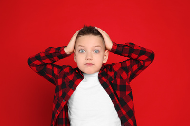 Portrait of emotional little boy on red background
