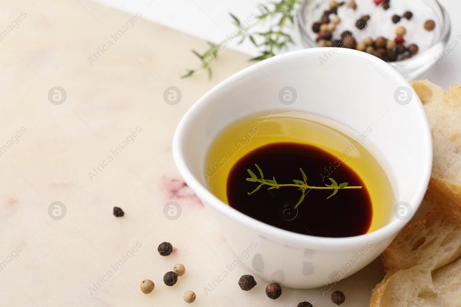 Photo of Bowl of organic balsamic vinegar with oil and spices served with bread slices on beige table. Space for text