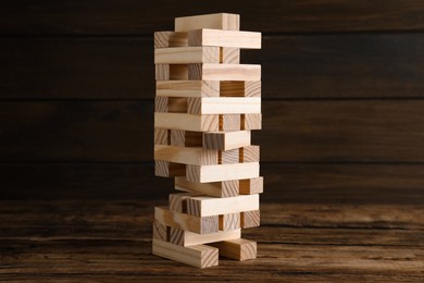Photo of Jenga tower made of wooden blocks on table