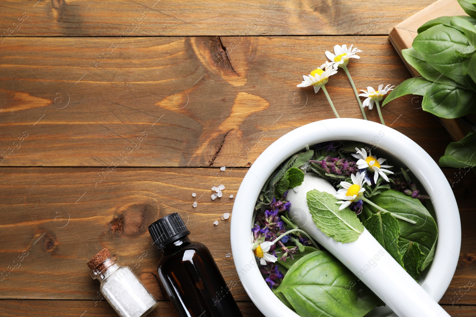 Photo of Flat lay composition with mortar and different healing  herbs on wooden table, space for text