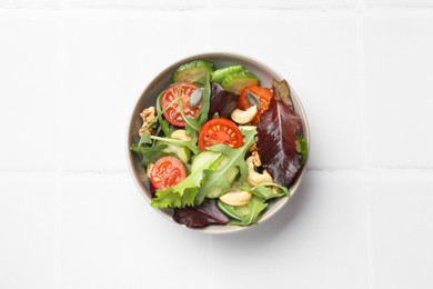 Photo of Tasty fresh vegetarian salad on white tiled table, top view