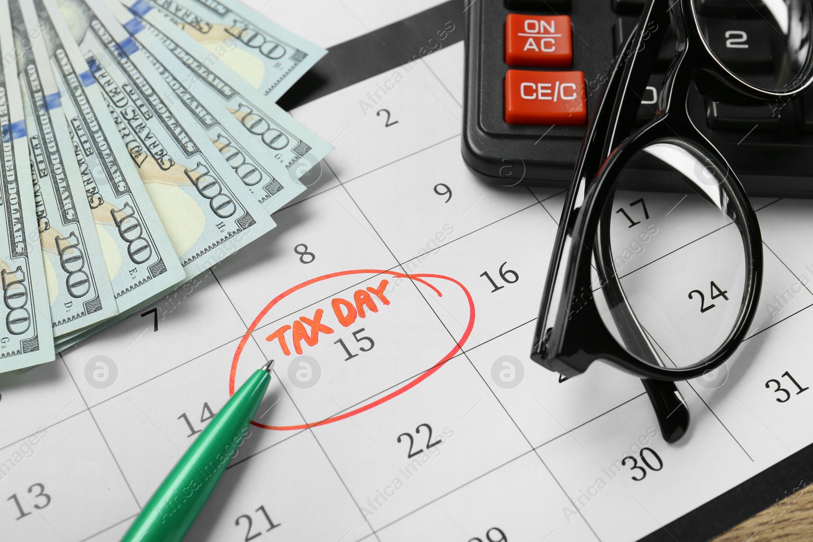 Photo of Calendar with date reminder about tax day, pen, glasses, money and calculator, closeup