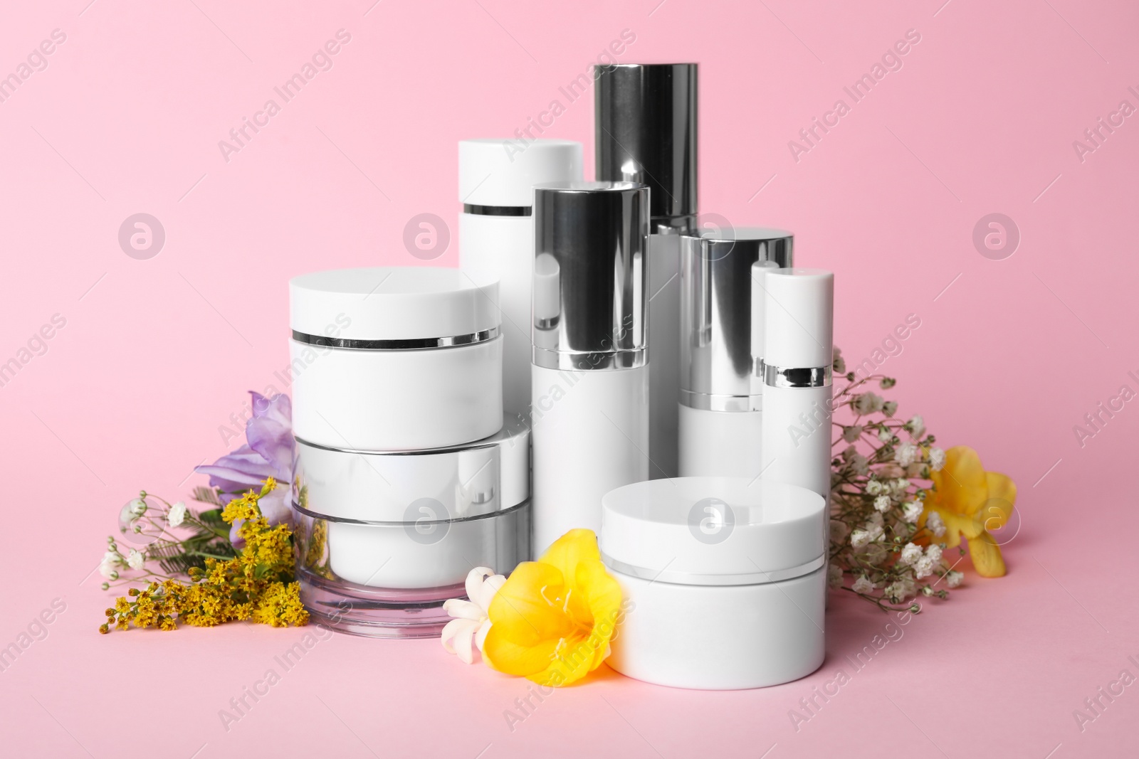 Photo of Set of luxury cosmetic products and flowers on pink background
