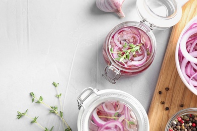 Photo of Flat lay composition with jars of pickled onions on light table. Space for text