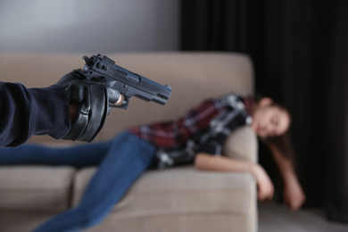 Photo of Man with gun and his victim indoors, closeup. Dangerous criminal