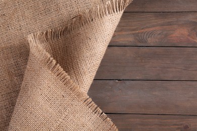 Beige burlap fabric on wooden table, top view. Space for text