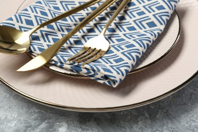 Photo of Clean plates, cutlery and napkin on light grey textured table, closeup