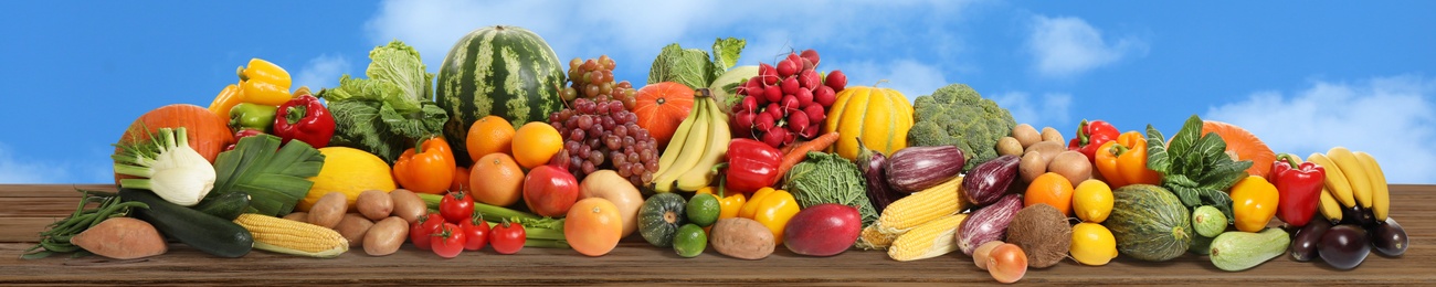 Image of Assortment of fresh organic fruits and vegetables on wooden table outdoors. Banner design