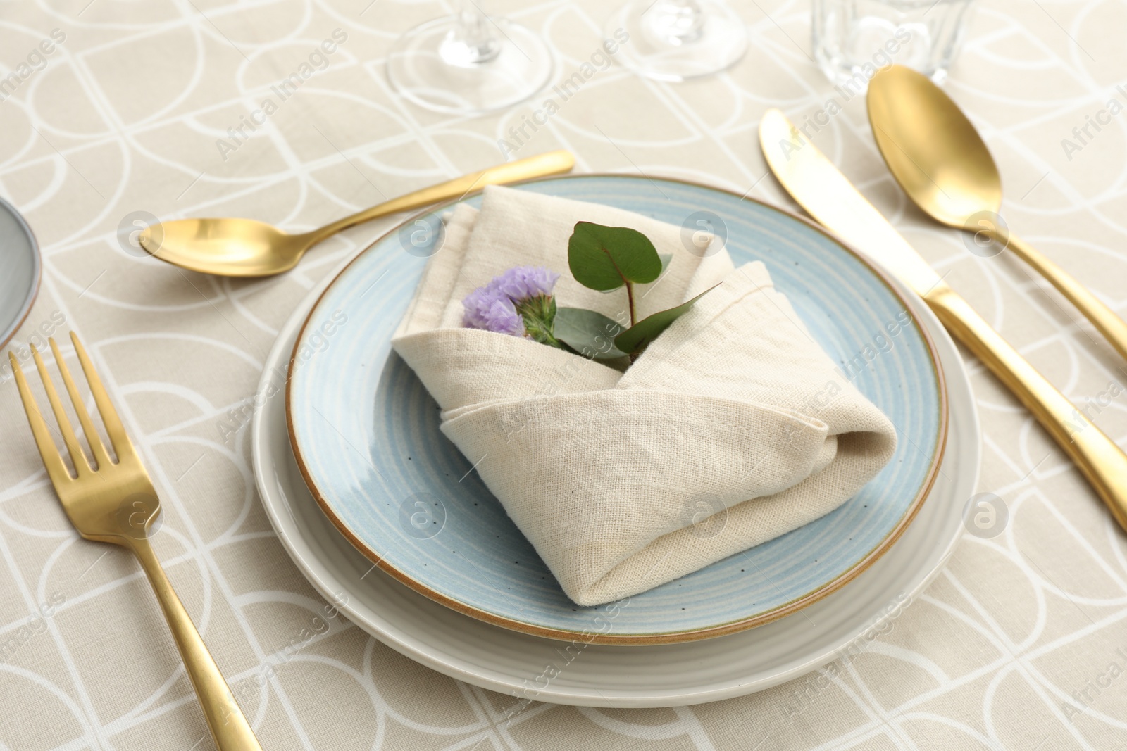 Photo of Stylish setting with cutlery, plates, napkin and floral decor on table