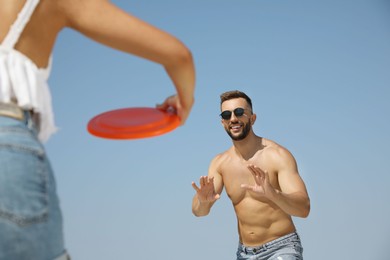 Couple playing with flying disk outdoors on sunny day