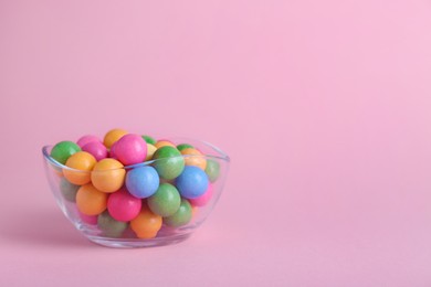 Photo of Bowl with many bright gumballs on pink background. Space for text