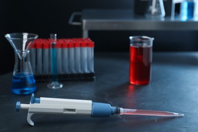 Photo of Laboratory analysis. Micropipette and different glassware on black table