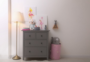 Chest of drawers and beautiful pictures in children's room, space for text. Interior design