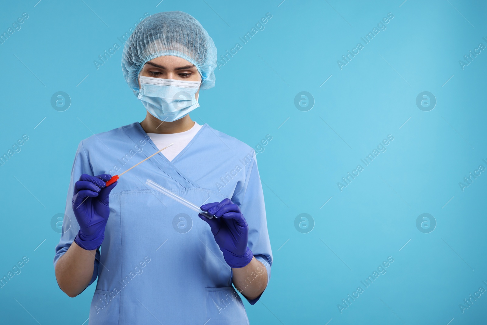 Photo of Laboratory testing. Doctor with cotton swab and tube on light blue background, space for text