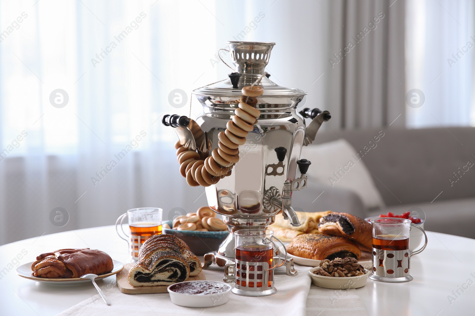 Photo of Traditional Russian samovar with treats on white table at home