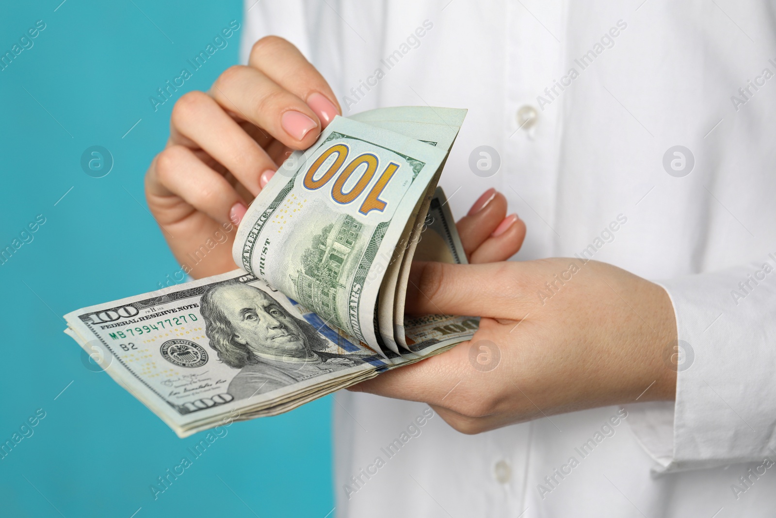 Photo of Woman counting dollar banknotes on turquoise background, closeup. Money exchange concept