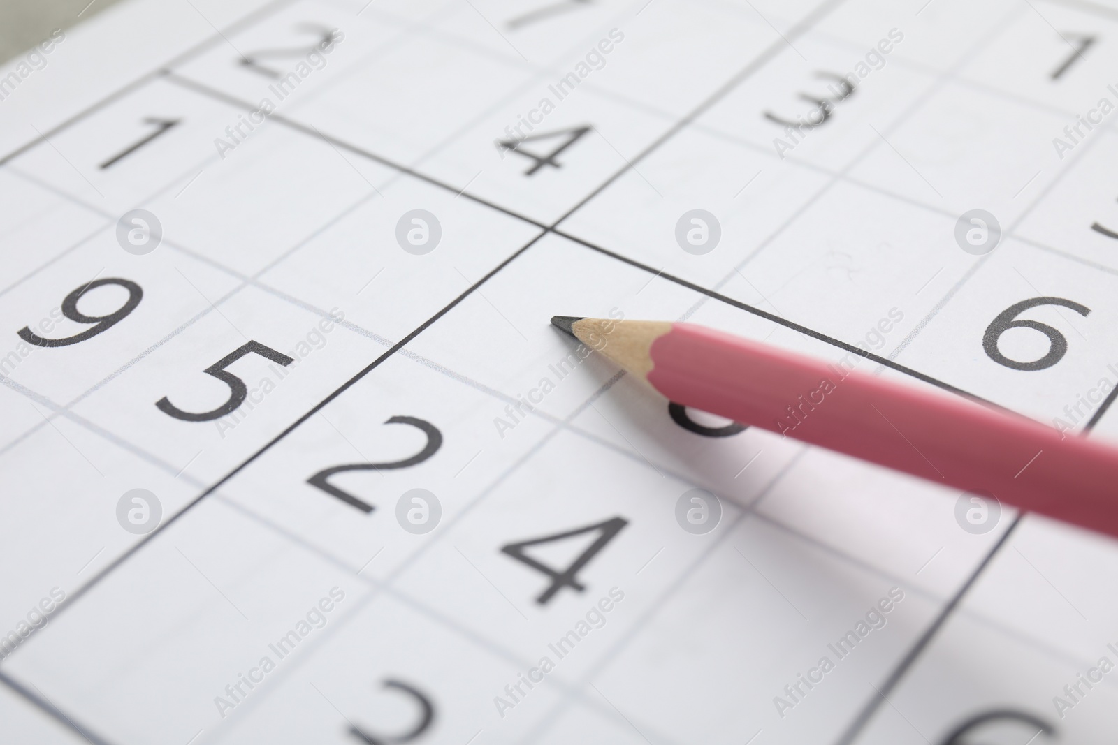 Photo of Sudoku puzzle grid and pencil, closeup view