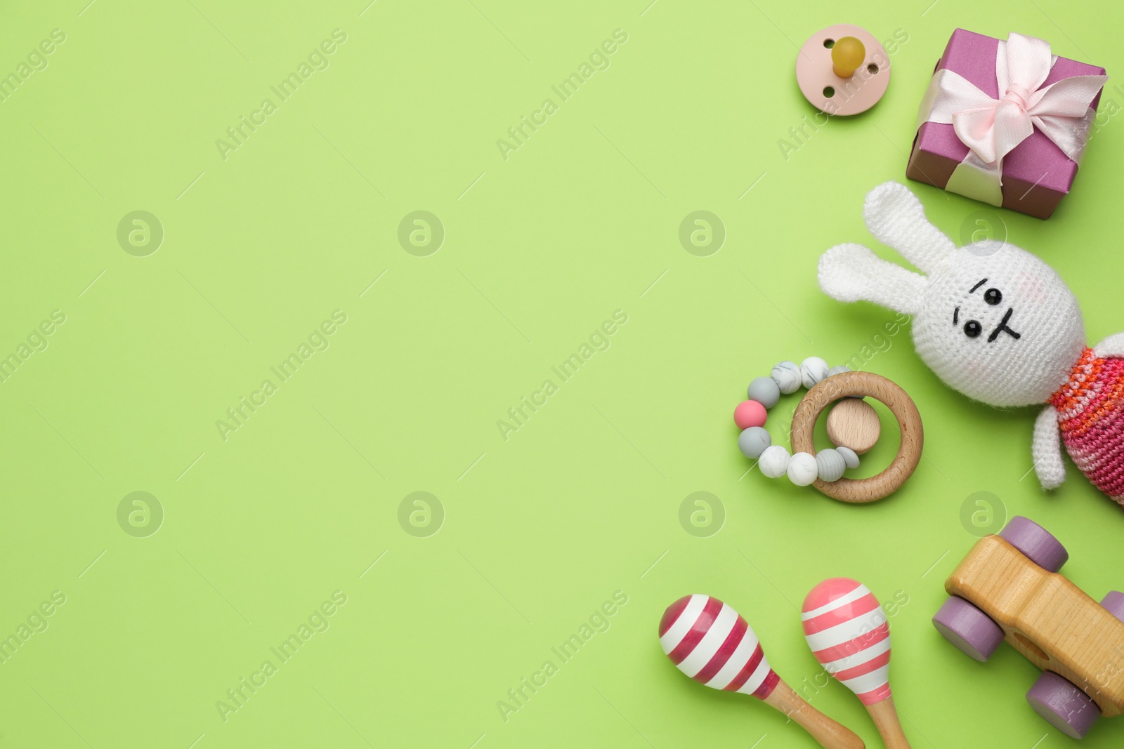 Photo of Gift box, pacifier and baby toys on light green background, flat lay. Space for text