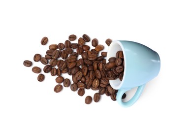 Photo of Overturned cup and roasted coffee beans on white background, top view