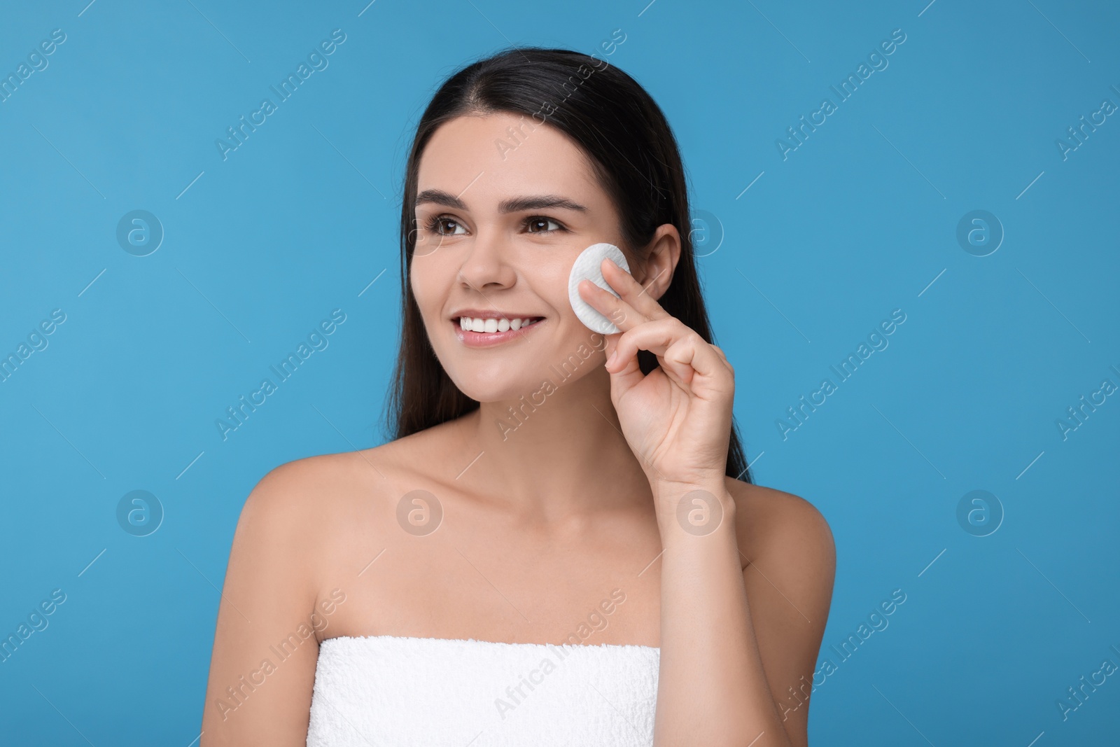 Photo of Young woman with cotton pad on light blue background