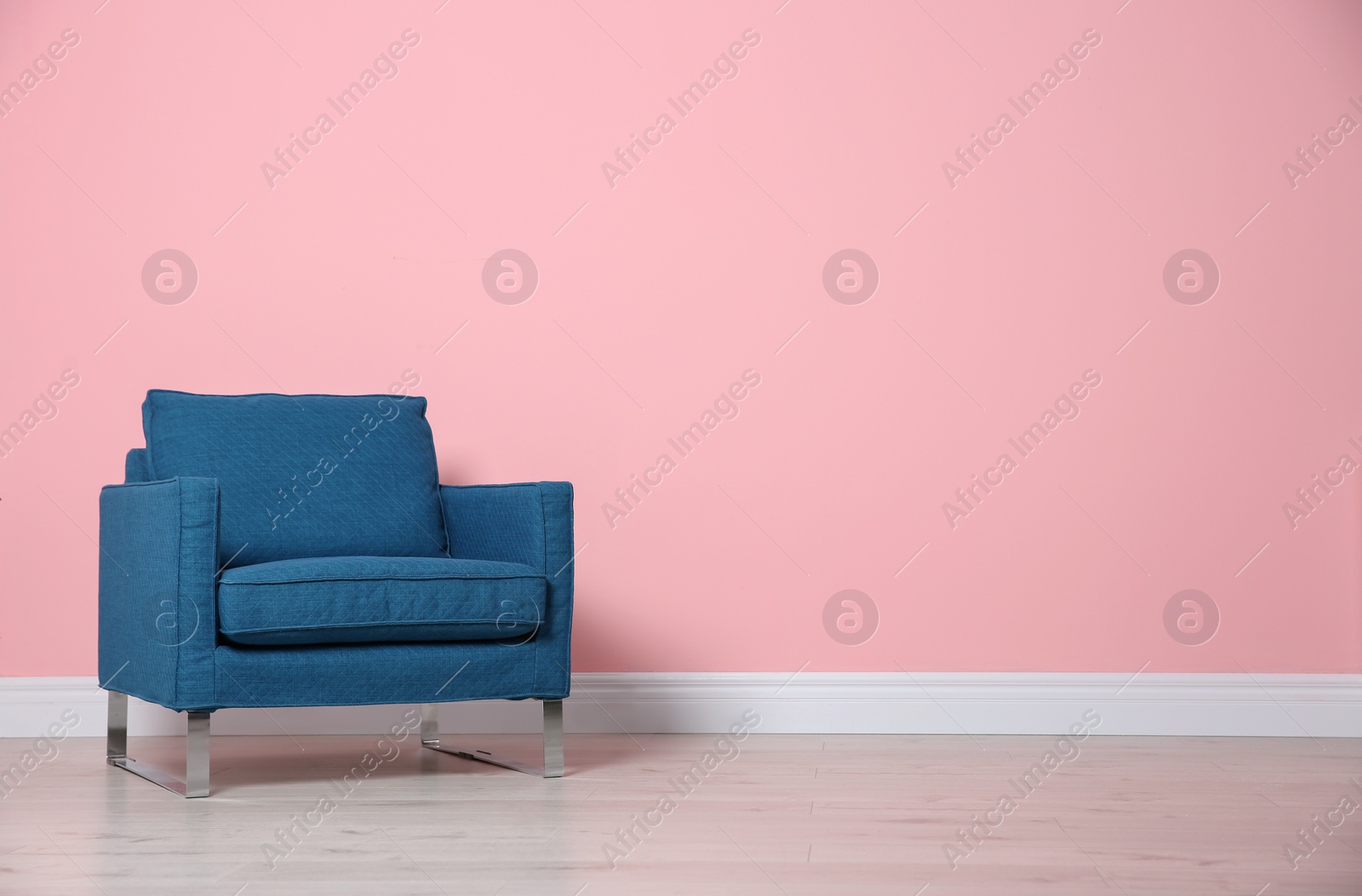 Photo of Comfortable armchair near color wall. Modern interior element