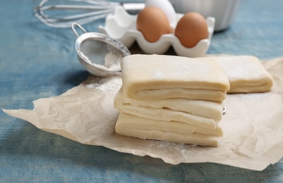 Photo of Parchment with raw wheat dough on table