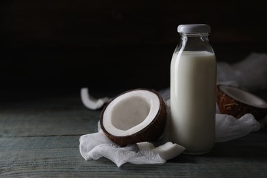 Photo of Bottle of coconut milk and nut on wooden table, space for text