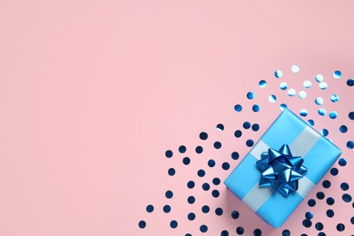 Light blue gift box and shiny confetti on pink background, top view. Space for text