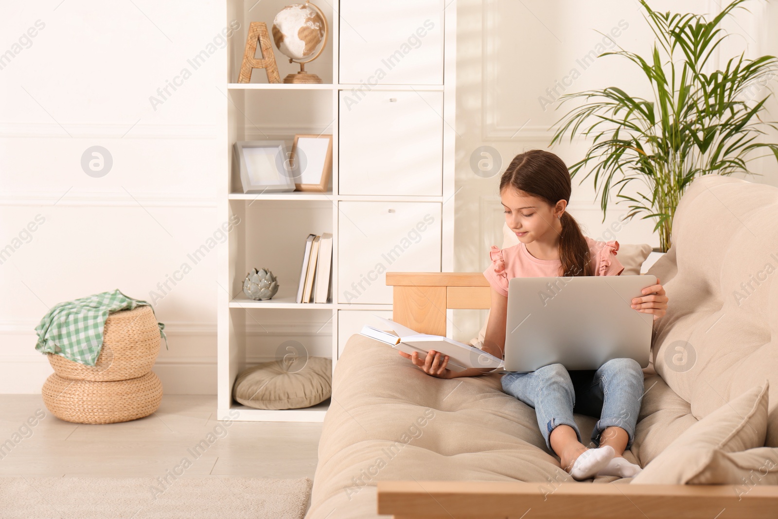 Photo of Girl with laptop and book on sofa at home