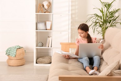 Photo of Girl with laptop and book on sofa at home