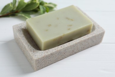 Photo of Soap bar and green leaf on white wooden table, closeup