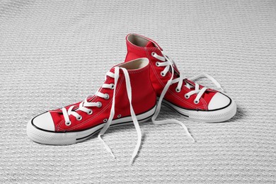 Pair of new stylish red sneakers on light grey fabric